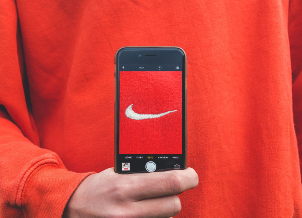 A phone zoomed in on a red sweatshirt with a white Nike swoosh logo
